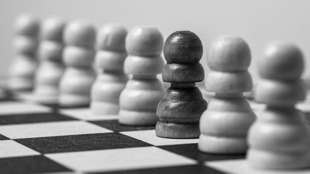 Een foto van een schaakbord met veel witte pionnen en één zwarte pion