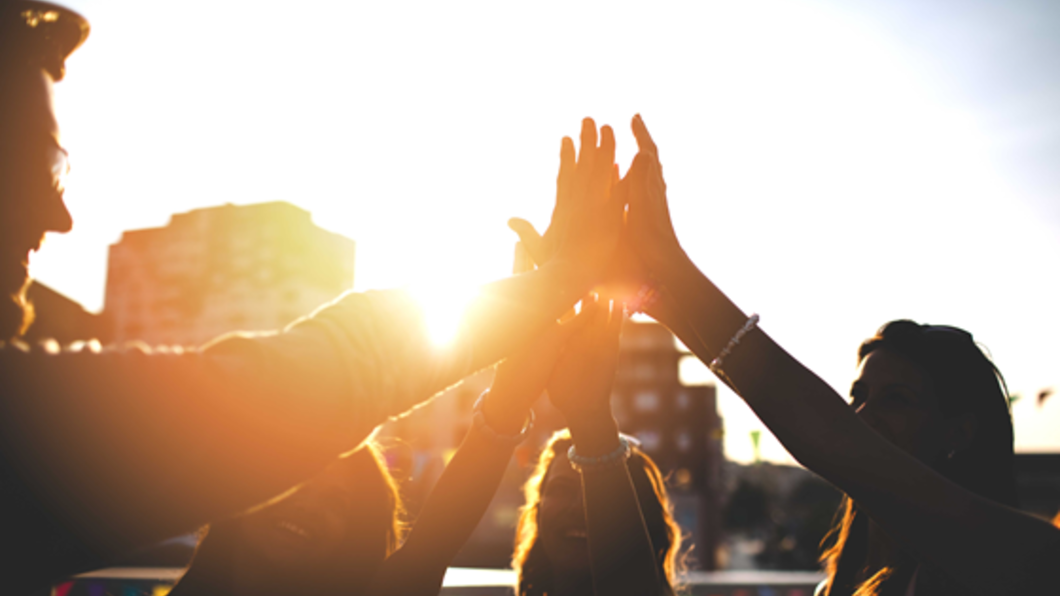 Mensen geven high five bij zonsondergang