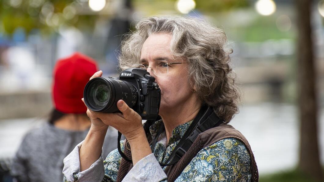 Vrouw met grijs haar houdt een fotocamera voor haar gezicht