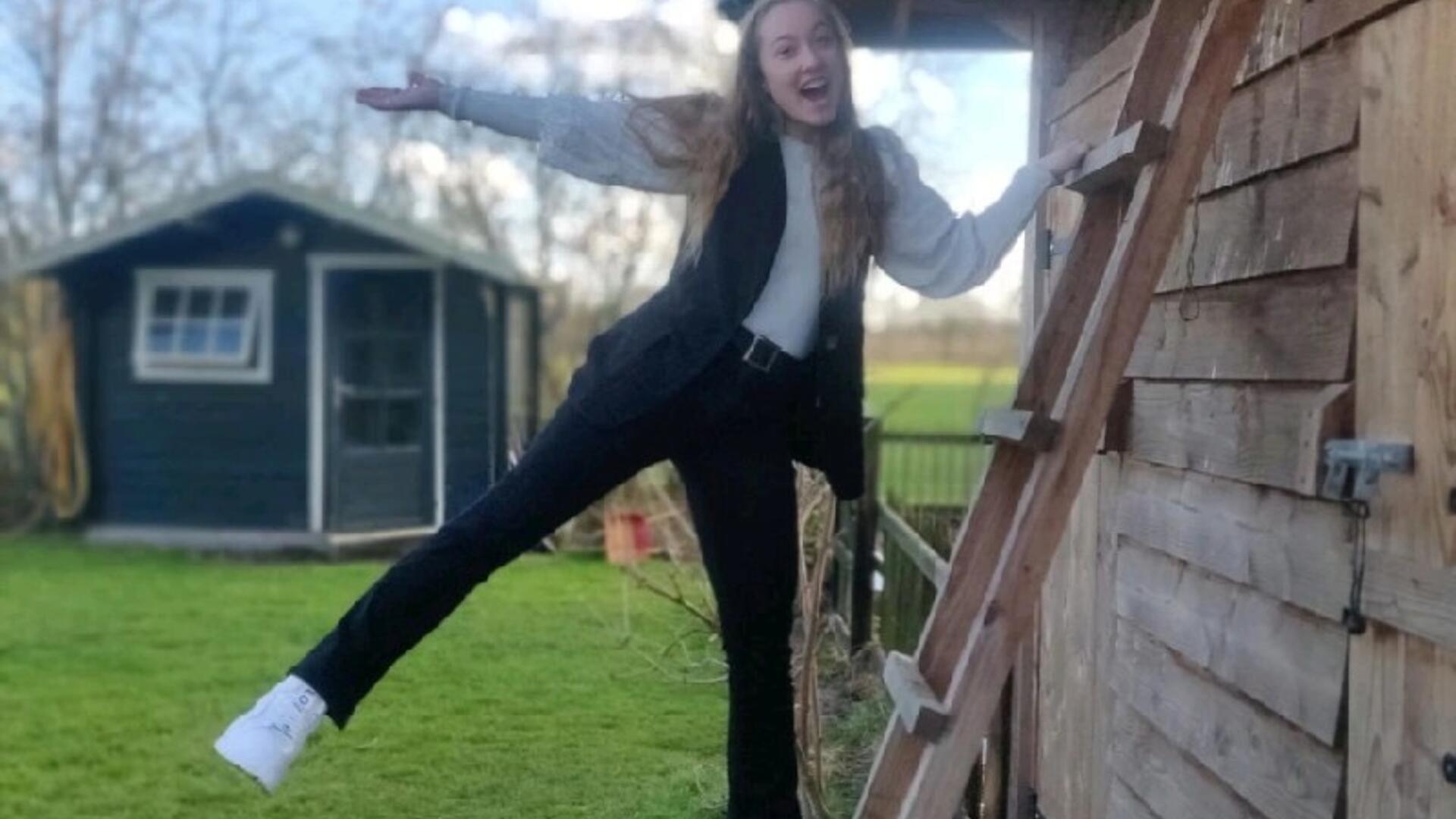 Foto Berit Weg die op een ladder tegen een schuur staat